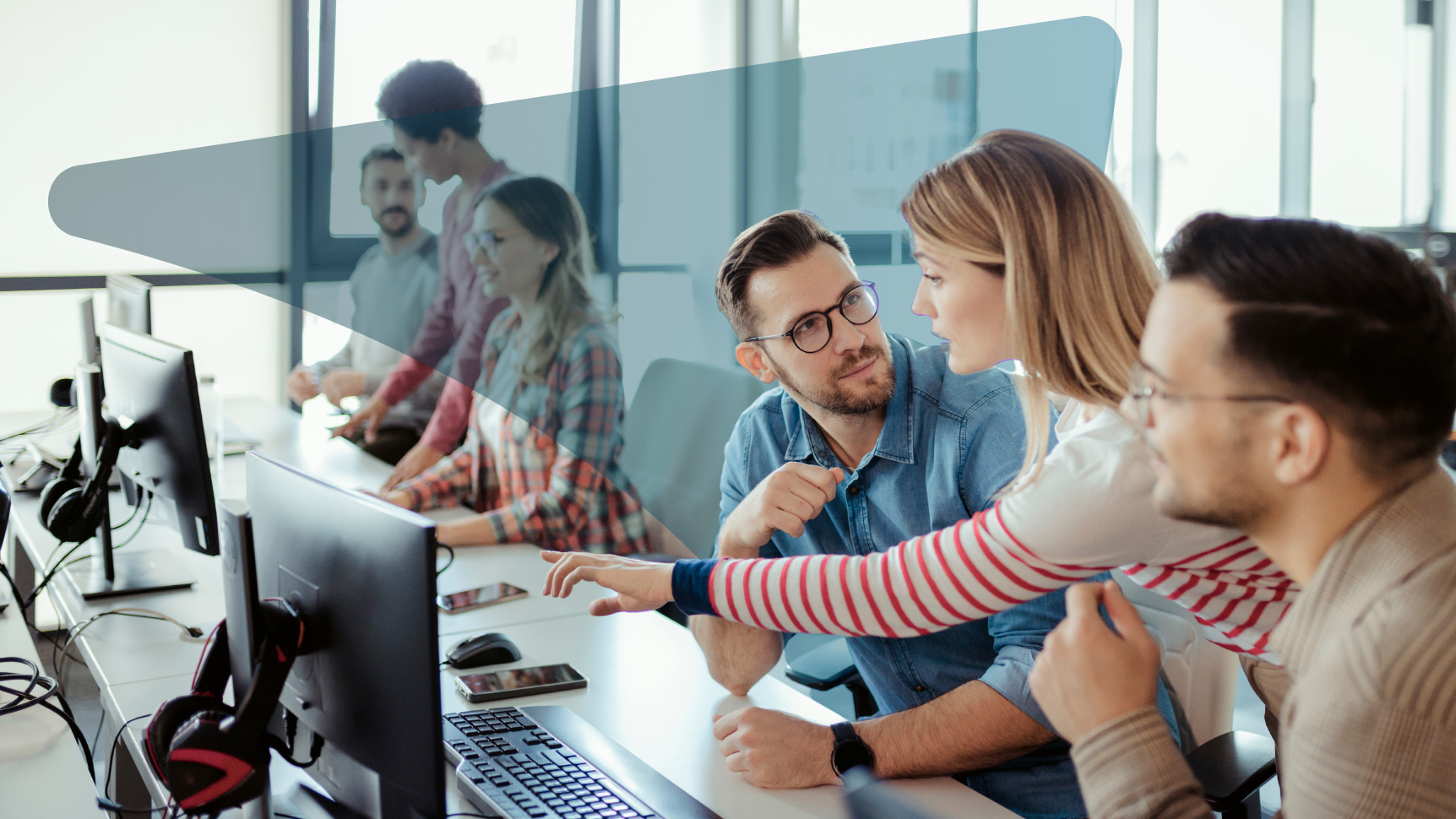 a group of people lean over a computer desk
