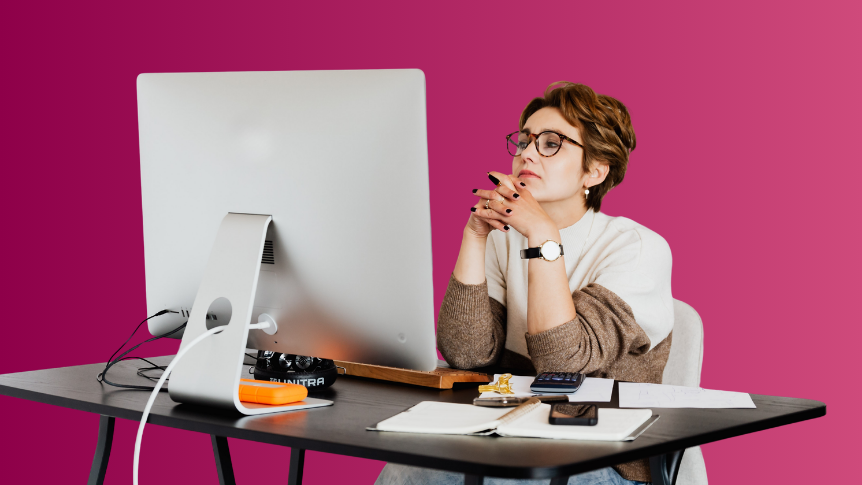 Woman with short hair and glasses looking wistfully at computer